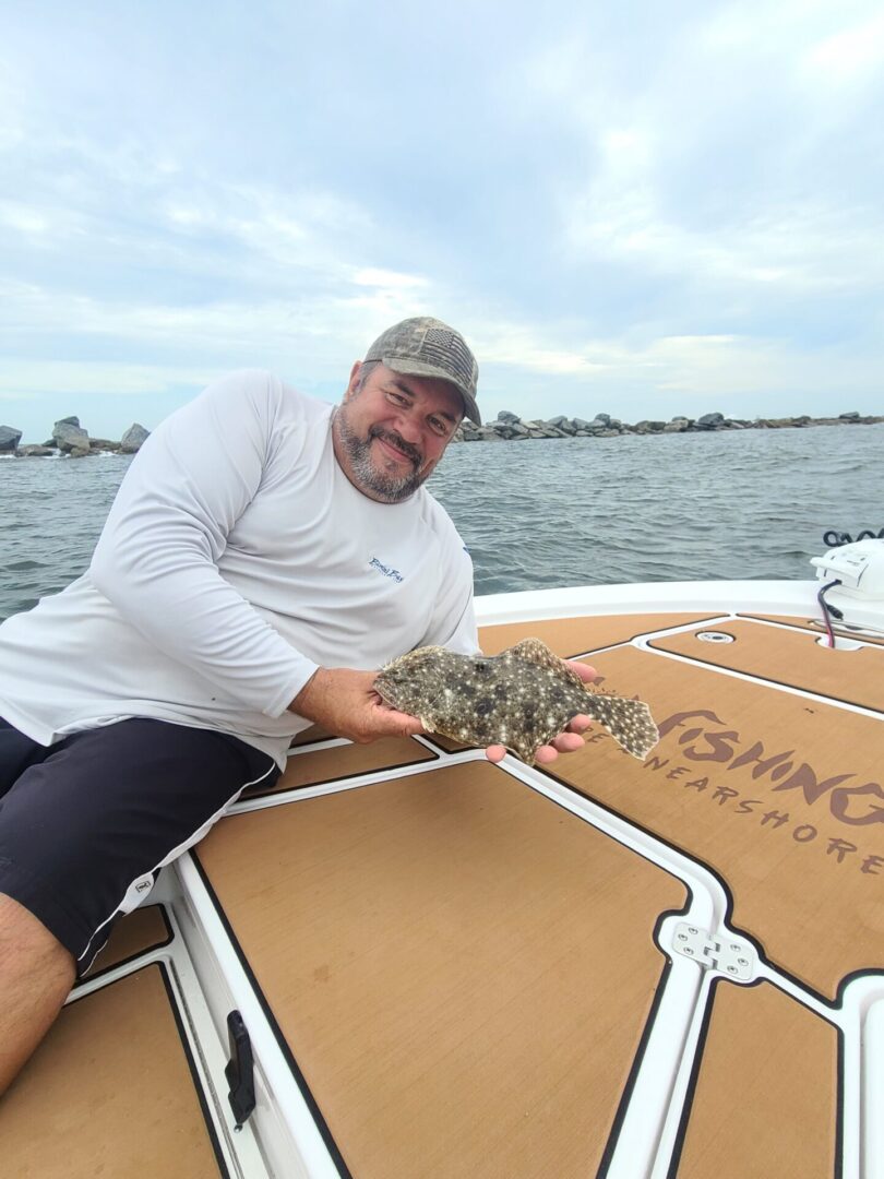A man holding a small sting ray on a boat