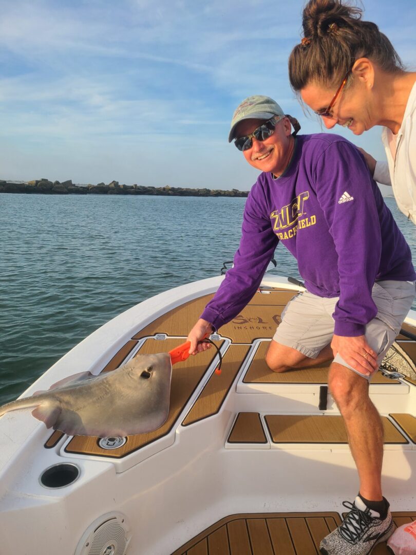 A man holding a sting ray on his boat