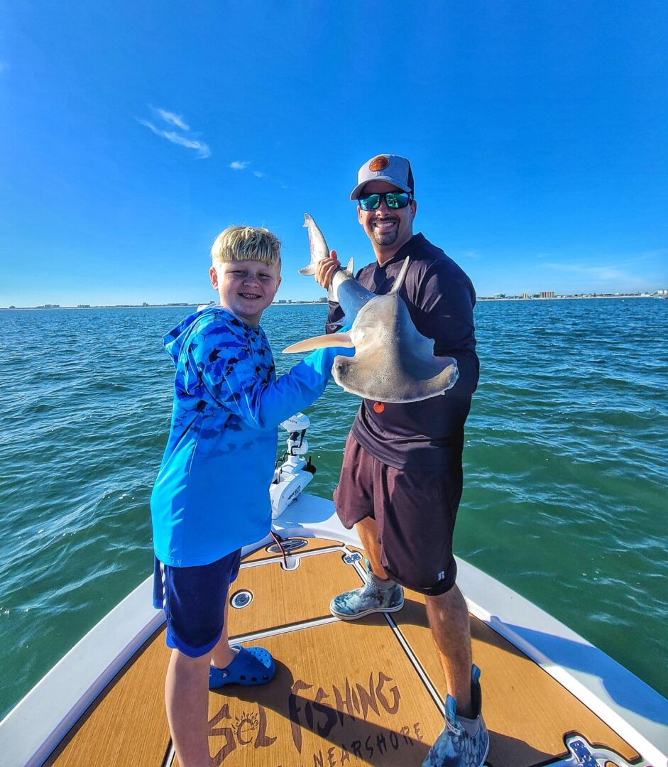 A man and a young boy holding a shark