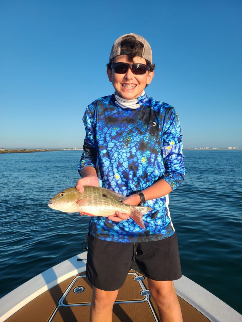 A boy with braces holding a fish