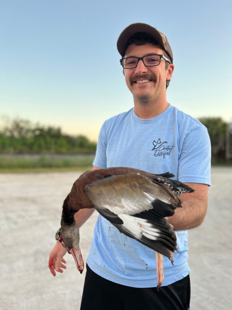 a man with a hat holding a dead duck