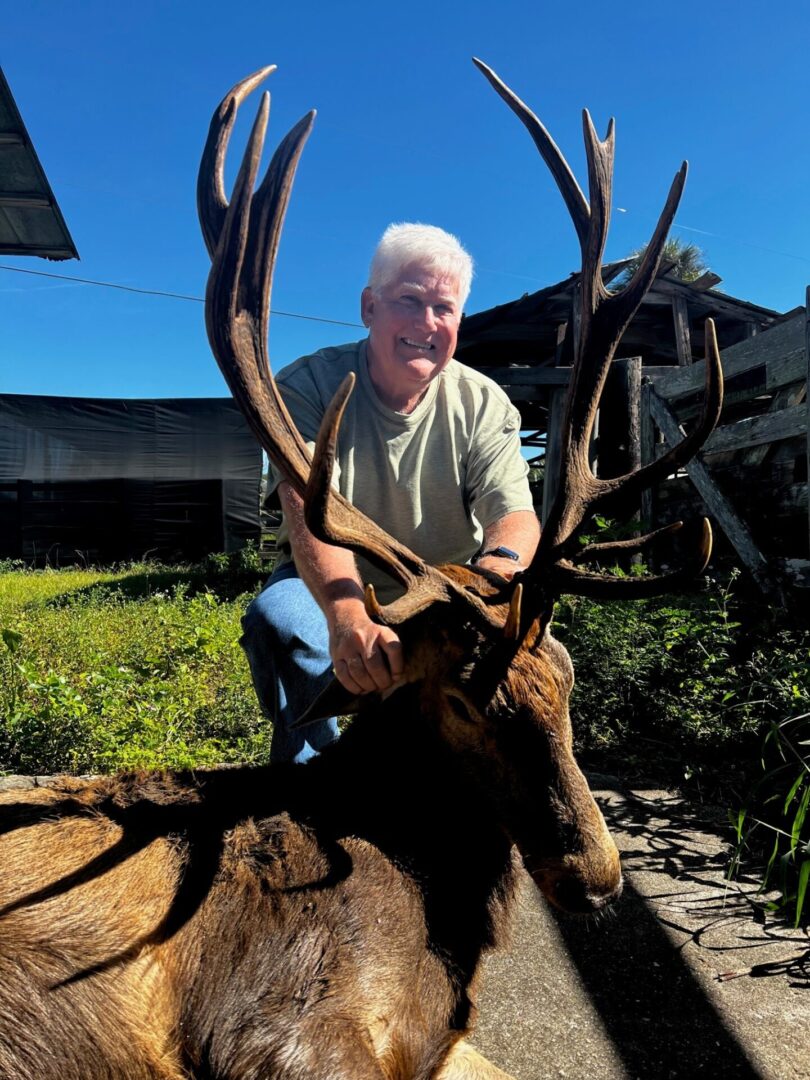 an elderly man posing with an elk