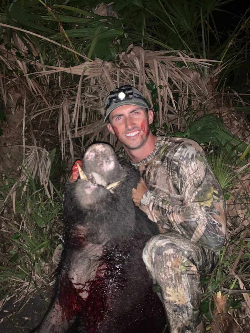 a hunter posing with dead Hog at night