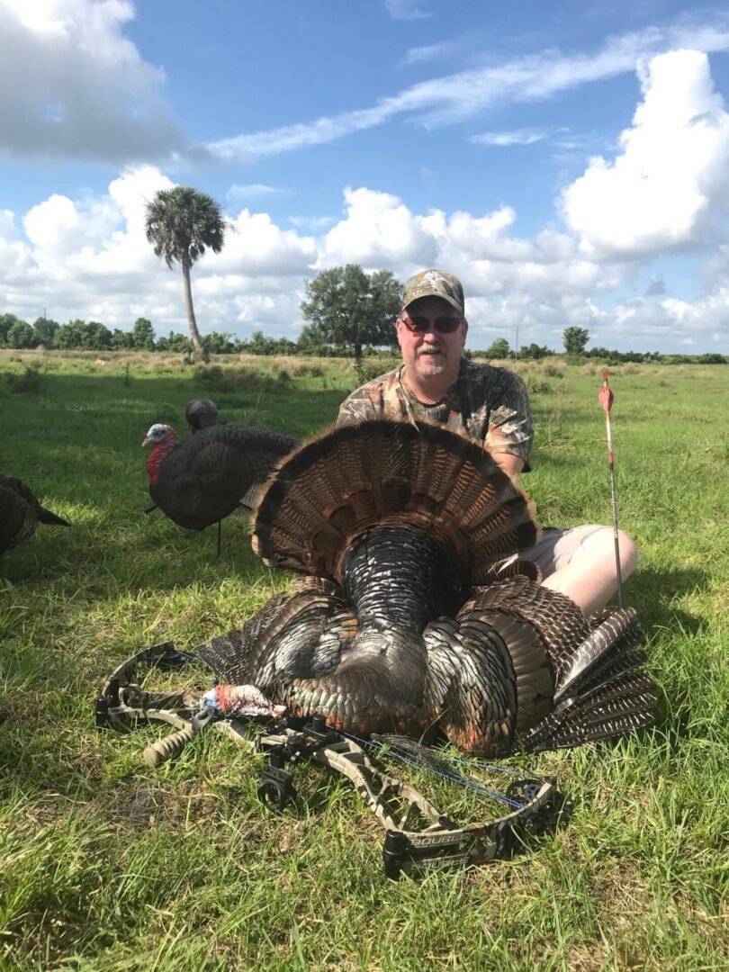 a man sitting on the ground with a dead Turkey